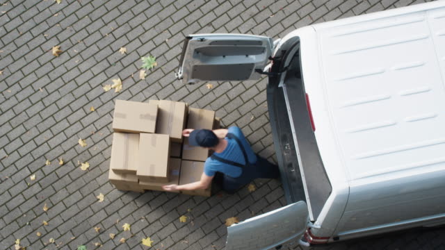 Delivery Man Loads his Commercial Van with Cardboard Boxes.