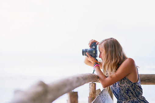 Shot of a young woman taking pictures while on holiday in Thailand