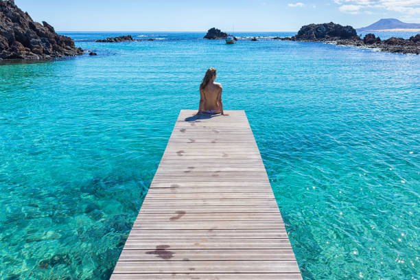 istock Topless girl on a pier clear transparent water 664968480