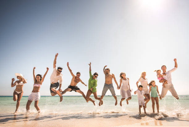 istock Large group of playful people jumping on the beach. 664972122