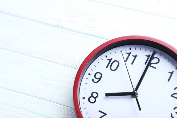 istock Red round clock on a white wooden table 664975316