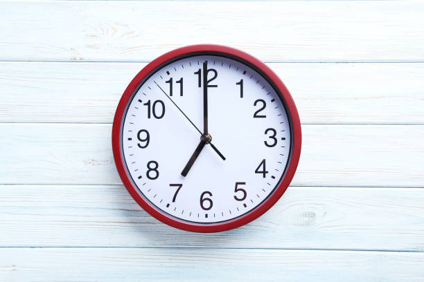 istock Red round clock on a white wooden table 664979830