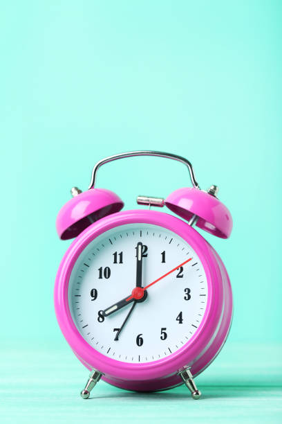 istock Pink alarm clock on a green background 664980096