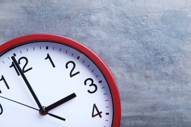 istock Red round clock on a grey wooden table 664980300