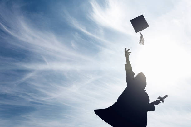 istock Graduate students tossing up hats over blue sky 664980350