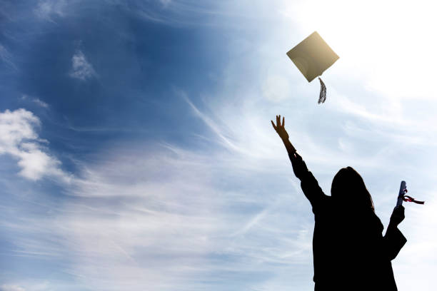 Graduate students tossing up hats over blue sky