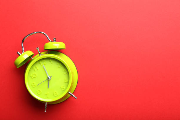 istock Green alarm clock on a red background 664980392
