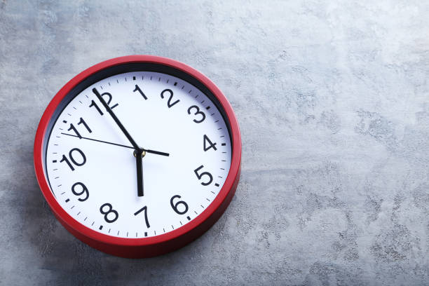 istock Red round clock on a grey wooden table 664980584