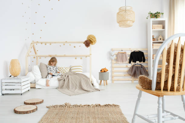 Girl sitting on her bed Little girl sitting on her bed in white scandinavian bedroom beige bedroom stock pictures, royalty-free photos & images