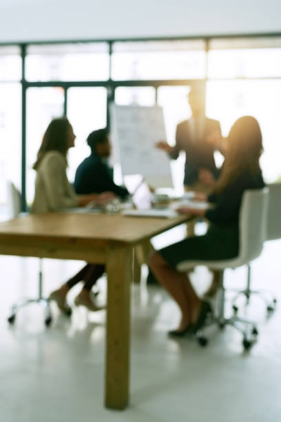 Meeting is session Shot of a group of corporate businesspeople meeting in the boardroom shareholders meeting stock pictures, royalty-free photos & images