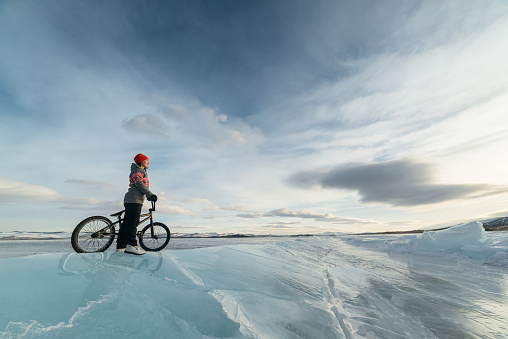 Girl standing on a bmx on the beautiful and dangerous ice.