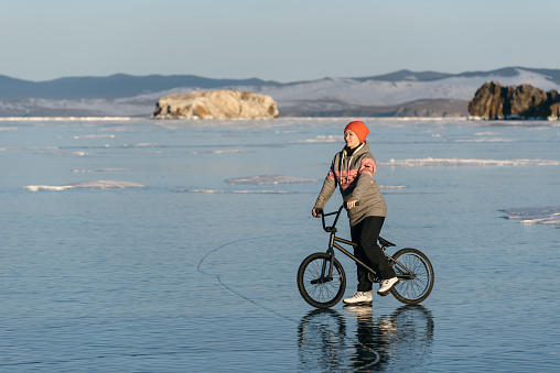 Girl standing on a bmx on the beautiful and dangerous ice.