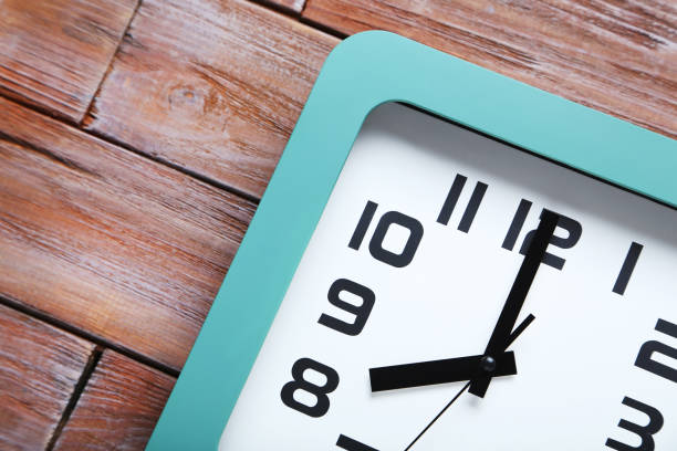 istock Green clock on a brown wooden table 664985612