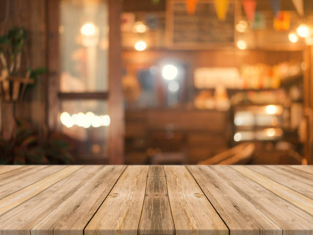istock Wooden board empty table top on of blurred background. Perspective brown wood table over blur in coffee shop background - can be used mock up for montage products display or design key visual layout. 664987018