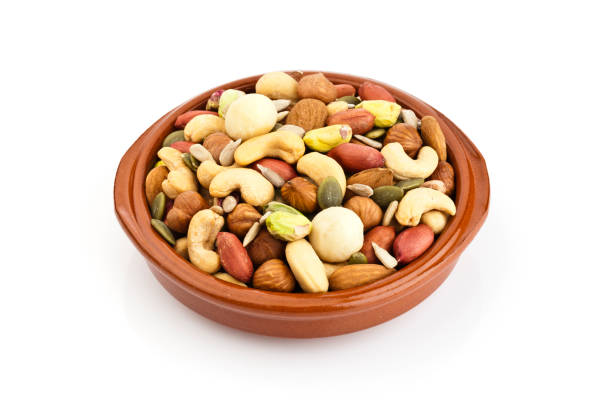Horizontal shot of a brown bowl filled with mixed nuts isolated on white background. Nuts included in the composition are pistachios, hazelnut, pine nut, almonds, pumpkin seeds, macadamia nuts, sunflower seeds, peanuts, cashew and walnuts. DSRL studio photo taken with Canon EOS 5D Mk II and Canon EF 100mm f/2.8L Macro IS USM