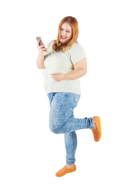 Full length of cheerful blonde woman with overweight body, reading message on her smartphone. Isolated on white background