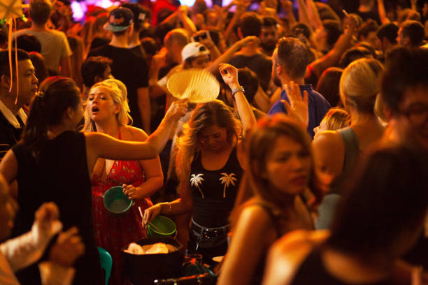 Dancing female tourists in crowd in Khao San Road Capture of dancing blonde female tourists in partying crowd in Khao San Road at deep night. Scene is between two main bars in Khao San Road. A thai woman is using fan for making some wind. khao san road stock pictures, royalty-free photos & images