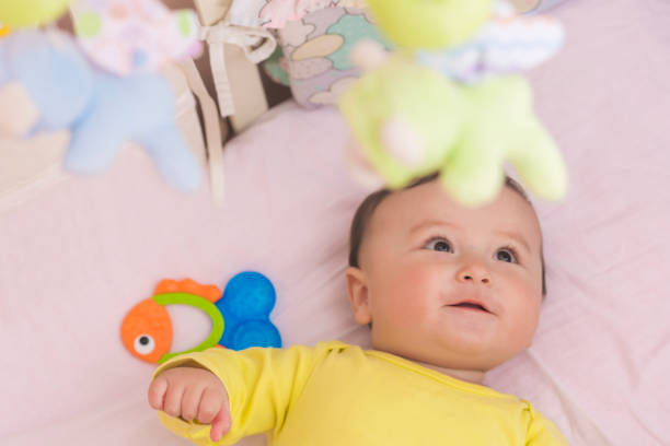 istock Baby lying in his crib reaching for toy curiously 664994502