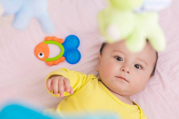 istock Baby lying in his crib reaching for toy curiously 664994628