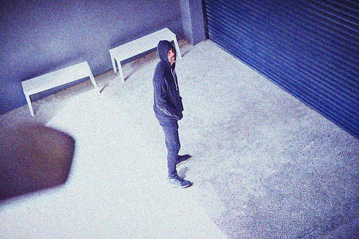 High angle shot of a sketchy-looking man standing outside a building