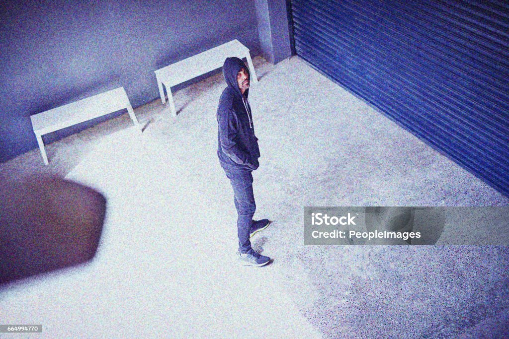 He's got crime on his mind High angle shot of a sketchy-looking man standing outside a building Security Camera Stock Photo
