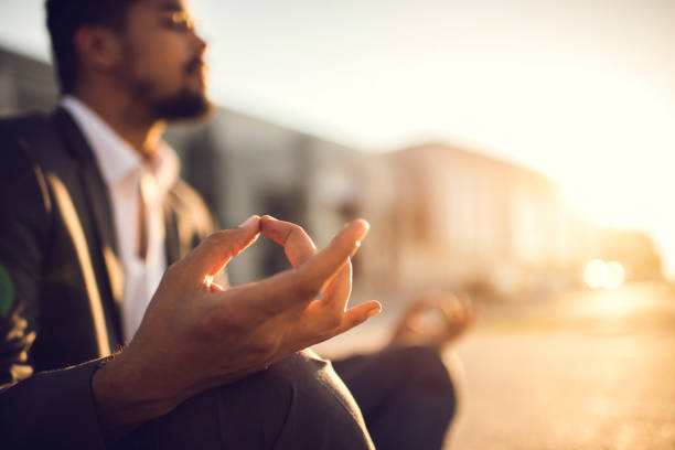 Close up of a businessman exercising Yoga at sunset. Close up of African American businessman meditating in Lotus position at sunset. meditation hands stock pictures, royalty-free photos & images