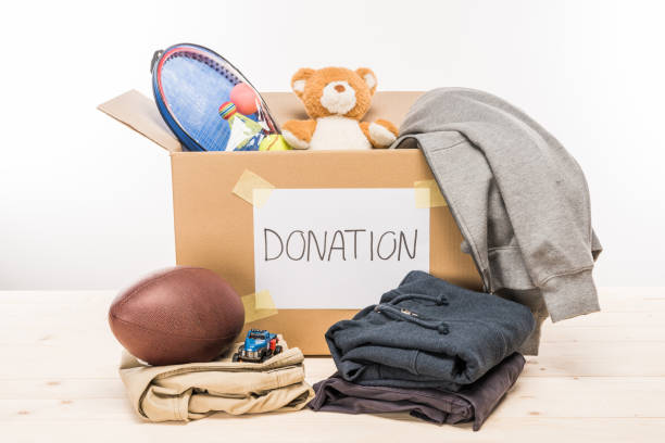 istock cardboard box with donation clothes and different objects on white, donation concept 664995210