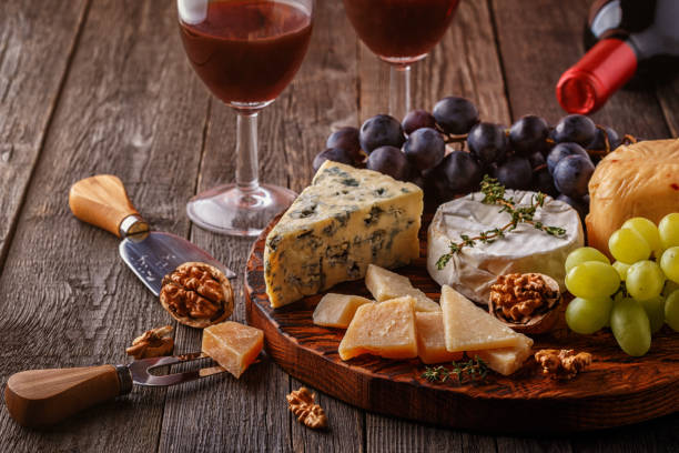 istock Cheese, nuts, grapes and red wine on wooden background 664998080