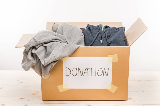 istock cardboard box with donation clothes on wooden table on white, donation concept 664998418