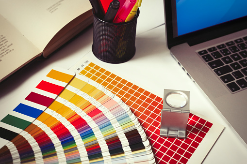 Creative designer, Graphic at workspace with digital tablet, color swatch samples and stationery on wooden table.
