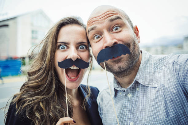 молодая привлекательная пара делает селфи - fake mustache стоковые фото и изображения