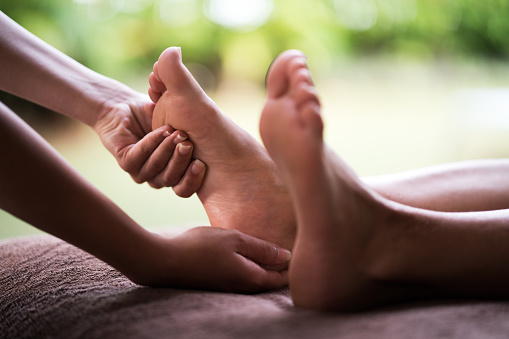 Close up of human hands massaging a woman's foot.