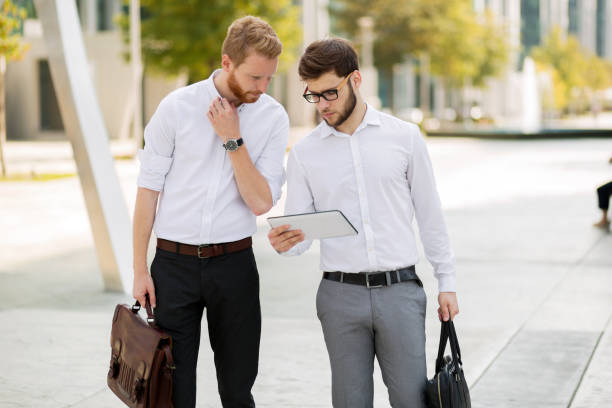 istock Business colleagues in shirt walking outdoors and using devices 665024938