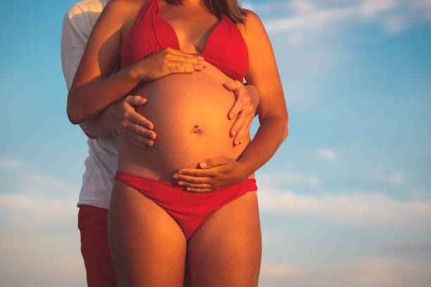 istock Happy pregnant couple at beach 665024940
