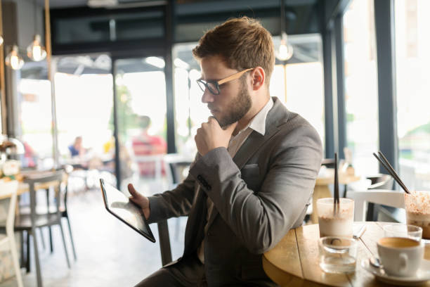 istock Smart businessman wearing suit using tablet in cafe 665025356