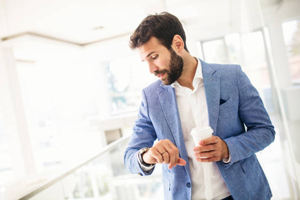 Young businessman checking the time Young male businessman looking at smart watch smart watch business stock pictures, royalty-free photos & images
