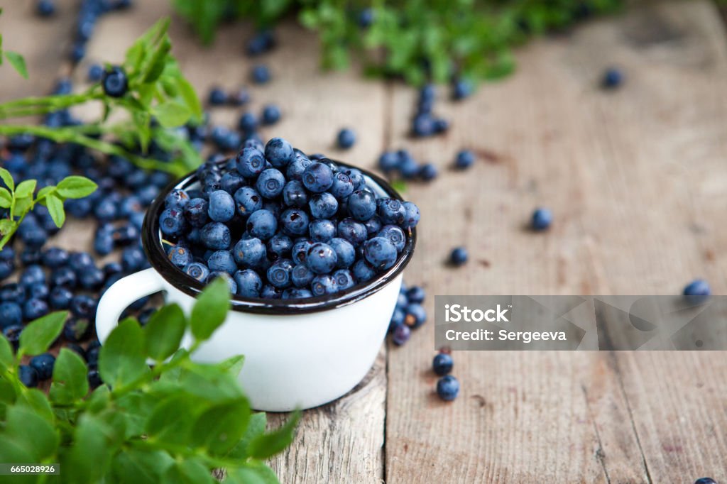 Blueberries Blueberries are scattered on a wooden table Blueberry Stock Photo