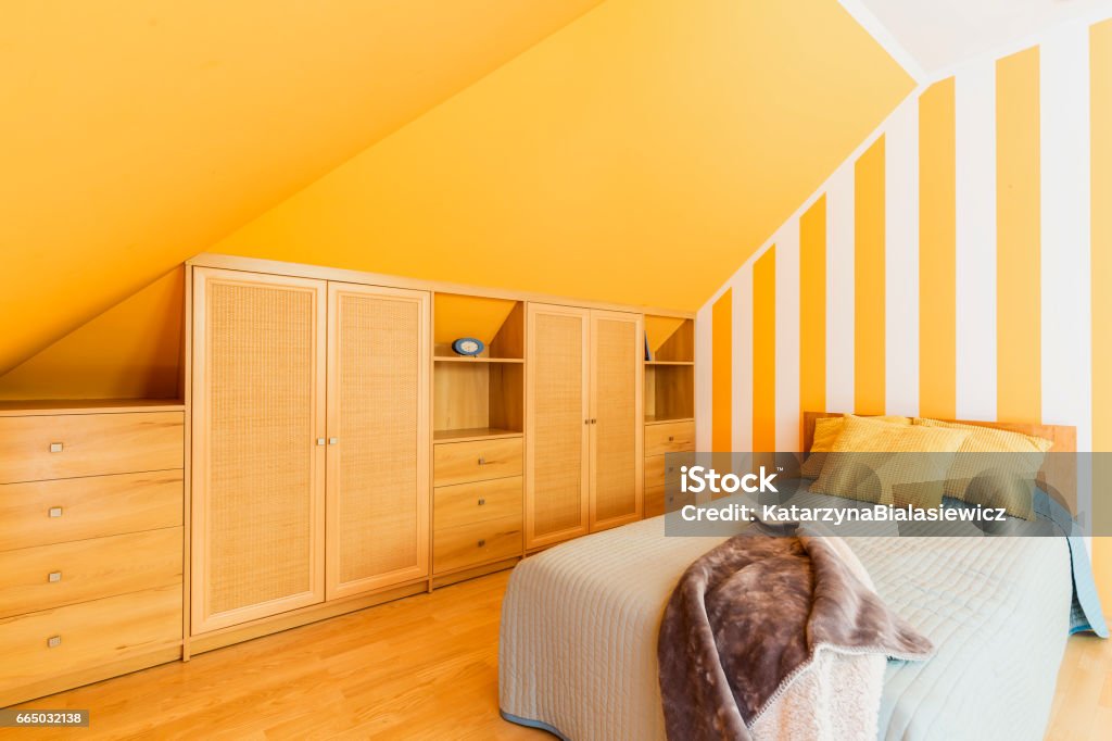 Attic bedroom with intense yellow walls Attic bedroom with intense yellow walls and fitted wardrobe Bedroom Stock Photo
