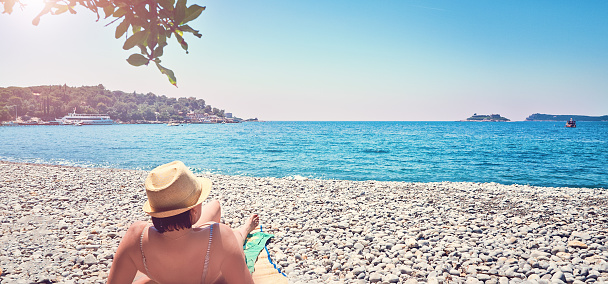 Woman sunbathes tanning beach  Zanjic Adriatik sea Montenegro  peninsula Lustica.