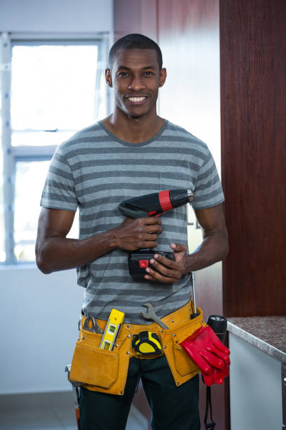 Smiling manual worker holding a drill machine Smiling manual worker holding a drill machine at home holding drill stock pictures, royalty-free photos & images