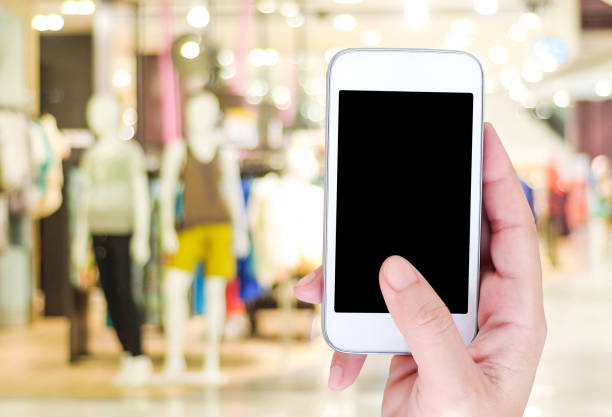 istock Hand holding smart phone over blur store background, e-commerce, smart pay, business and technology concept 665045530