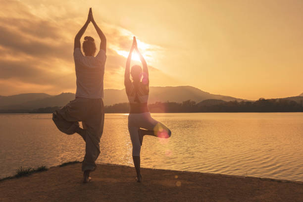 istock Man and woman practicing yoga at sunset 665047424