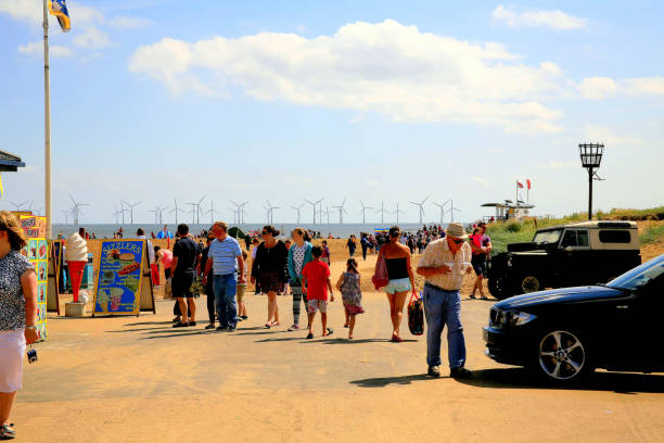 Skegness, Lincolnshire, UK. August 06, 2013 Holidaymakers  using a busy entrance to the beach facing a wind farm at Skegness in Lincolnshire.