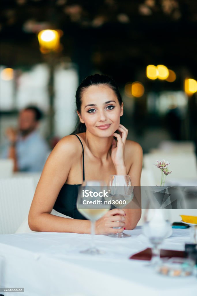 Beautiful woman sitting in restaurant and holding a glass of wine Luxury Stock Photo