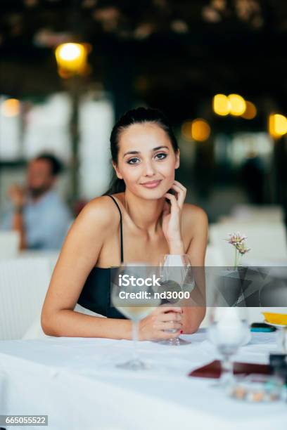 Beautiful Woman Sitting In Restaurant And Holding A Glass Of Wine Stock Photo - Download Image Now