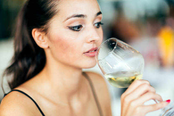 istock Attractive woman tasting wine while sitting in restaurant 665055590