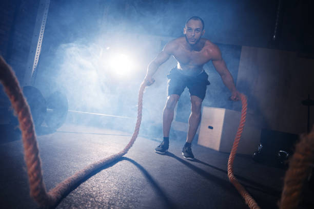 istock Full length of man tossing gym ropes 665059072