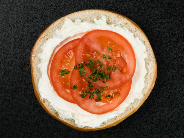 Bagel With Cream Cheese and Tomato Against a Black Background