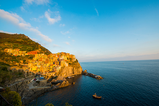 Manarola on cliffs above Ligurian Sea. Beautiful view of village on mountain against blue sky. It is one of the famous tourist attractions in Italy.