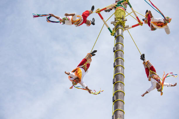 Cancun, Mexico - Mar 15, 2017: Traditional flying birdmen performance by voladores: performers throw themselves off a tall wooden pole while rotating towards the ground as part of a ritual ceremony to ask for fertility.